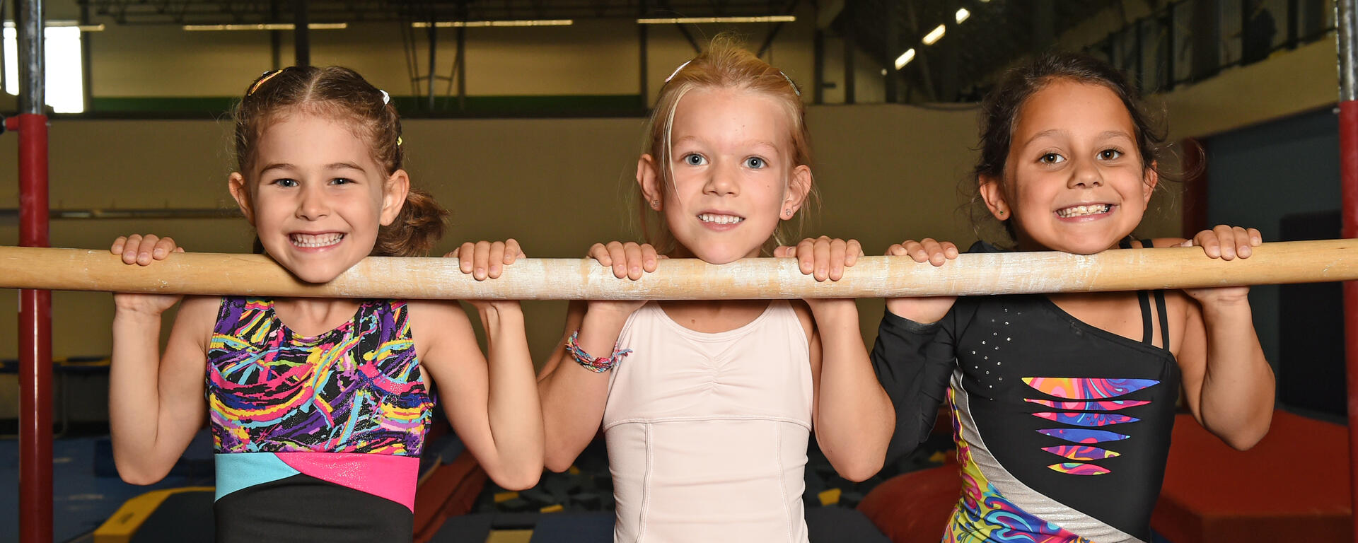 three girls hanging on gym bars