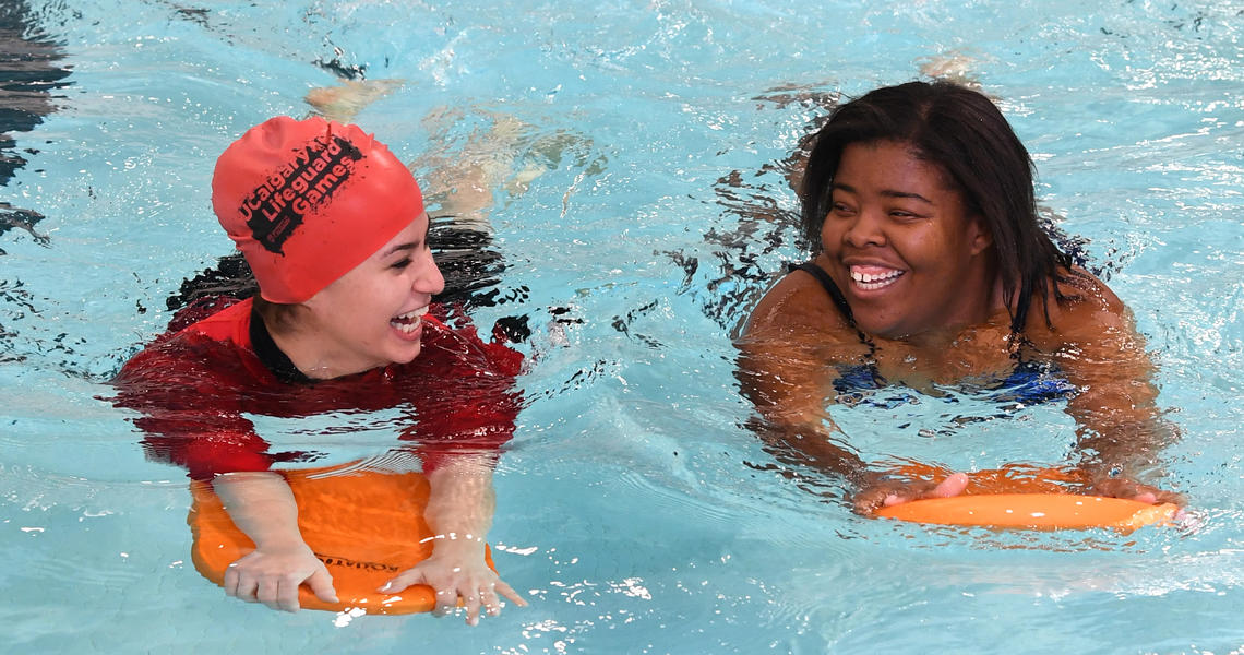 Two women swimming with flutter boards
