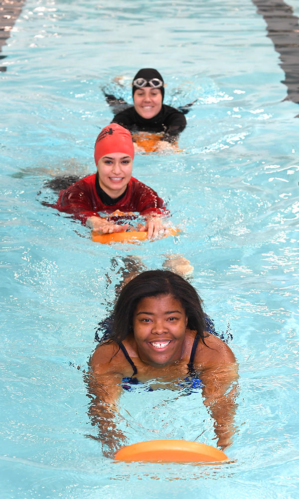 Three women swimming laps with flutter boards Three women swimming laps with flutter boards