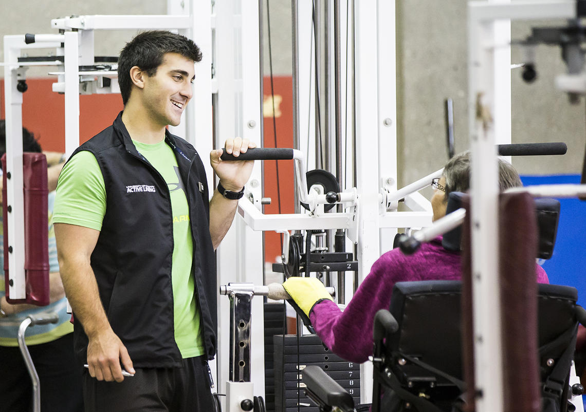 Trainer helps UCalgary Rehabilitation Fitness Program participant with stretches