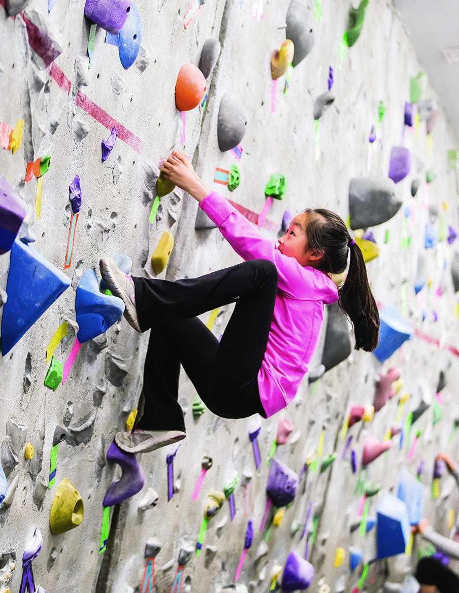 Girl scaling UCalgary bouldering wall