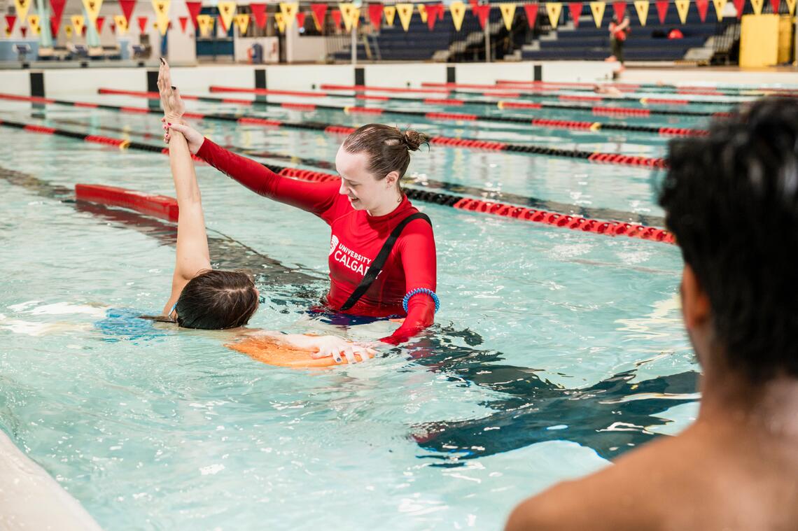 A swimming instructor teaching a student to swim 